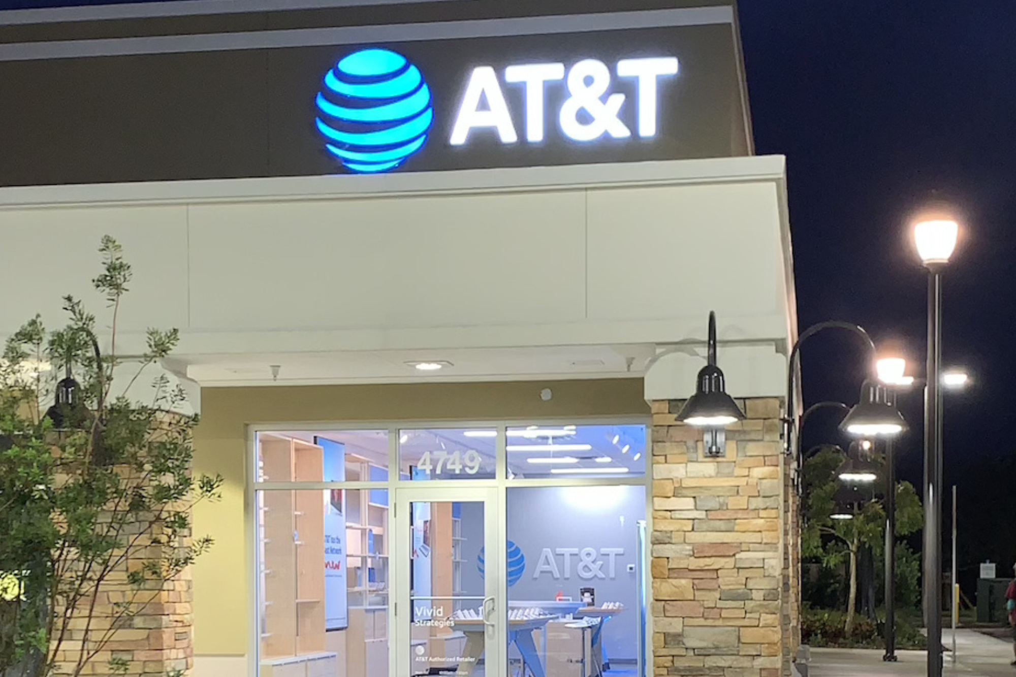 Exterior of an AT&T retail store at night with illuminated signage and storefront lighting.