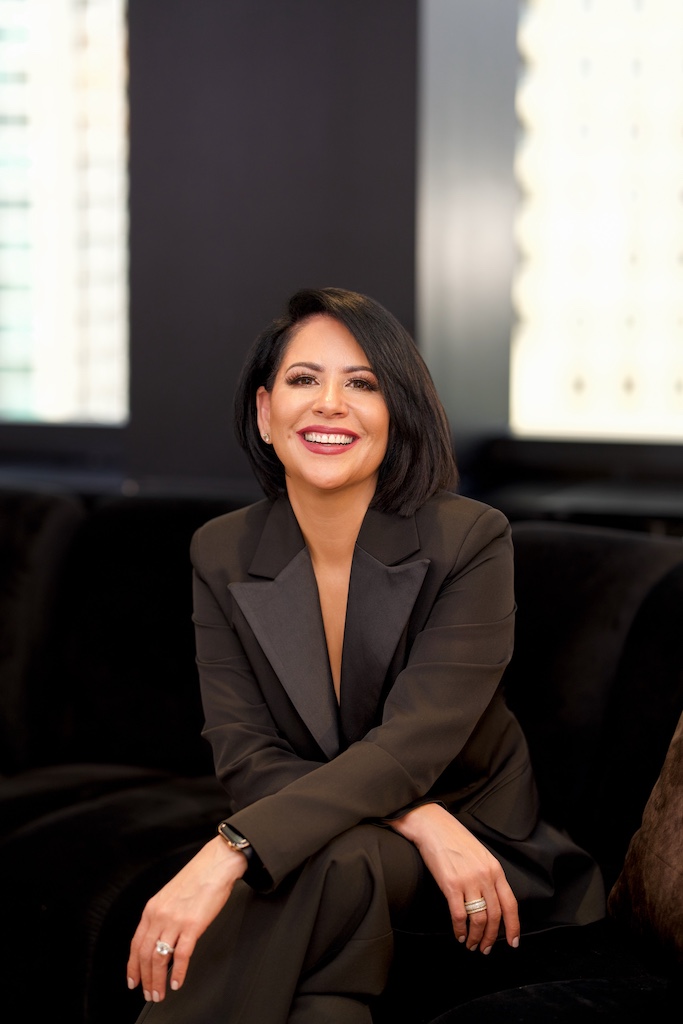 Professional portrait of Vivian Delgado-Johnson seated and smiling, showcasing confident leadership and executive presence